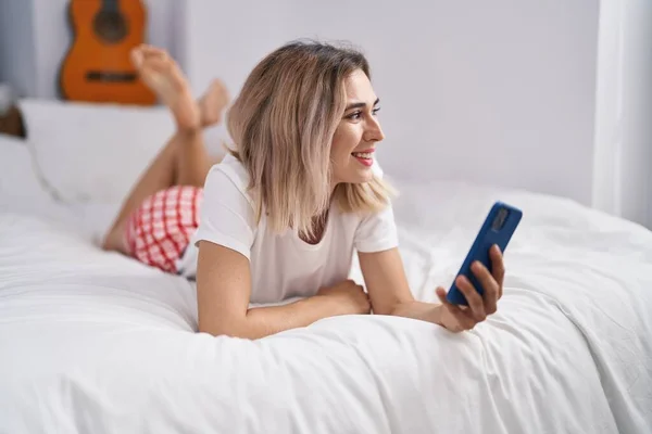 Νεαρή Γυναίκα Που Χρησιμοποιεί Smartphone Ξαπλωμένη Στο Κρεβάτι Στο Υπνοδωμάτιο — Φωτογραφία Αρχείου