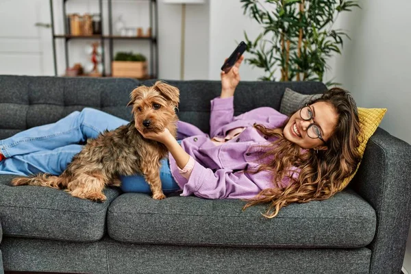 Young Beautiful Hispanic Woman Using Smartphone Lying Sofa Dog Home — Fotografia de Stock