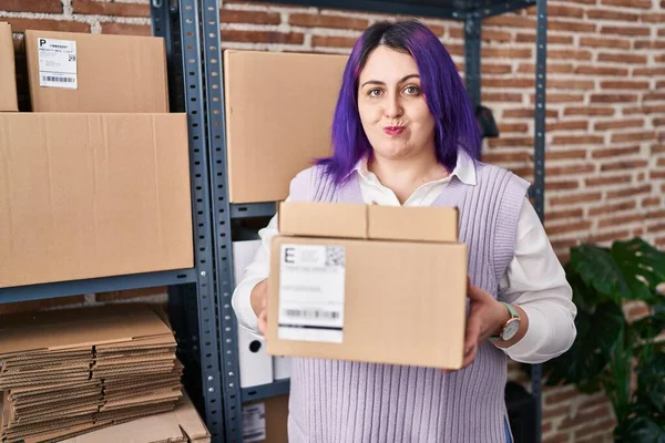 另外一个身材魁梧的女人是在小企业工作的紫色头发 手里拿着装有笑脸的盒子 嘴被空气吹胀 — 图库照片