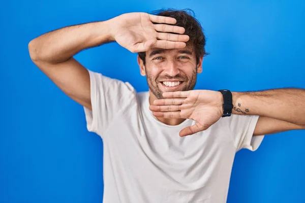 Hispánský Mladík Který Stojí Nad Modrým Pozadím Radostně Usmívá Vykukuje — Stock fotografie