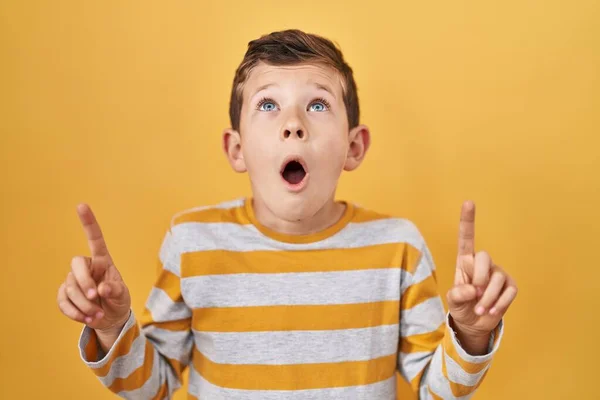 Sarı Arka Plan Üzerinde Duran Genç Beyaz Çocuk Şaşırmış Şaşırmış — Stok fotoğraf
