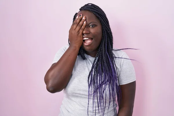 ピンクの背景に立っている若いアフリカの女性は 半分の顔 口を手で覆い疲れてあくびをしています 痛みで顔が痛い — ストック写真