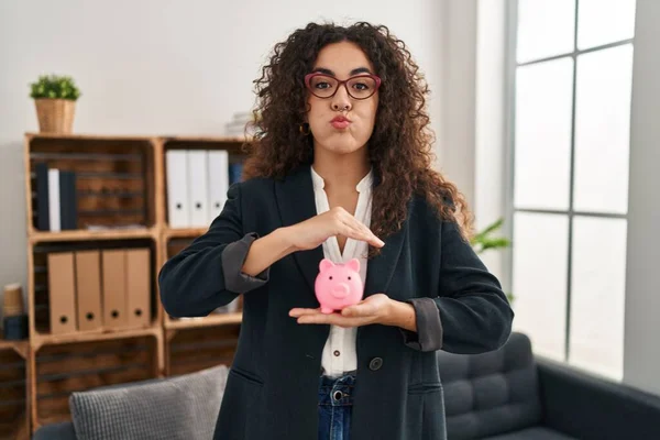 Young Hispanic Woman Holding Piggy Bank Puffing Cheeks Funny Face — Stock Photo, Image