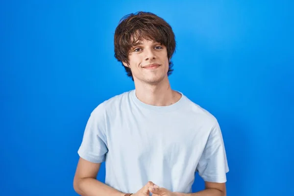 Hispanic Young Man Standing Blue Background Hands Together Crossed Fingers — Stockfoto