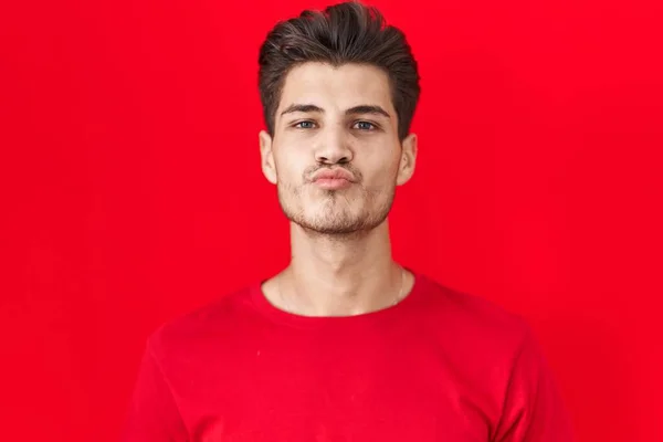 Giovane Uomo Ispanico Piedi Sfondo Rosso Guardando Fotocamera Soffiando Bacio — Foto Stock