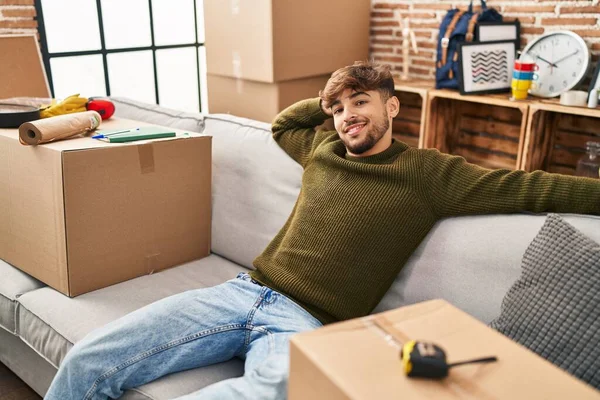 Young arab man smiling confident relaxed on sofa at new home