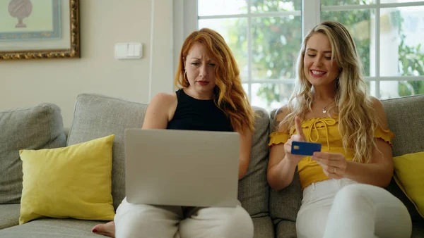 Two women using laptop and credit card at home