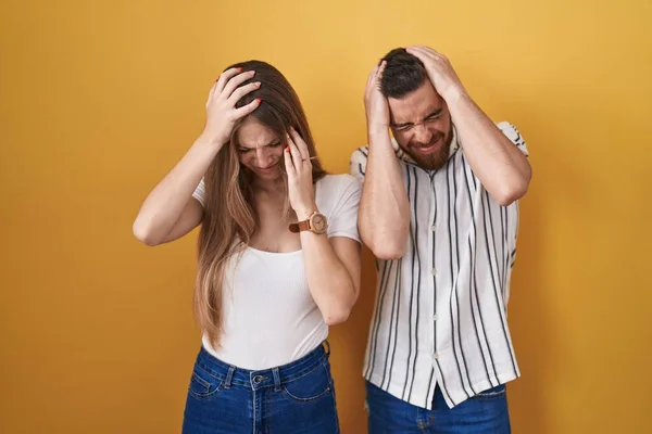 Junges Paar Das Vor Gelbem Hintergrund Steht Und Unter Kopfschmerzen — Stockfoto