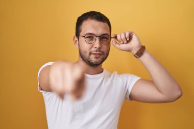 İspanyol gözlüklü adam kamerayı işaret ediyor ve sen kendine güvenen, ciddi görünüyorsun. 