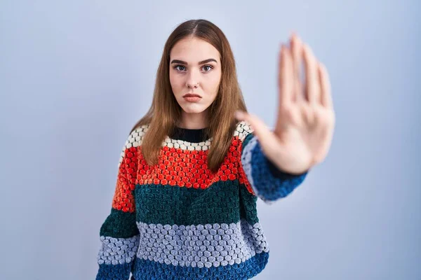 年轻的惊慌失措的女孩站在蓝色的背景上 用手掌停止歌唱 用消极而严肃的手势警告人 — 图库照片