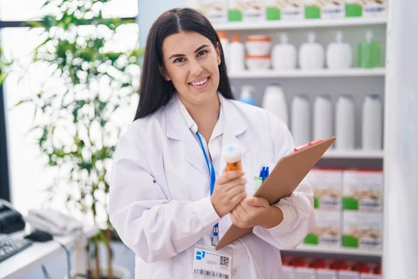 Молодая Красивая Латиноамериканка Фармацевт Держит Бутылку Таблетками Чтение Документа Аптеке — стоковое фото