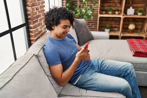Jovem Hispânico Usando Smartphone Sentado Sofá Casa — Fotografia de Stock