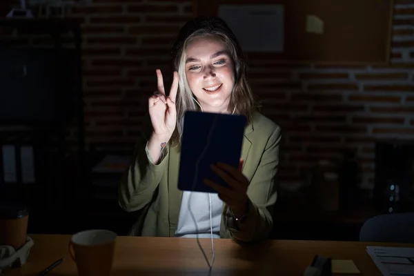 Geceleri Ofiste Çalışan Sarışın Beyaz Bir Kadın Kameraya Bakıp Zafer — Stok fotoğraf