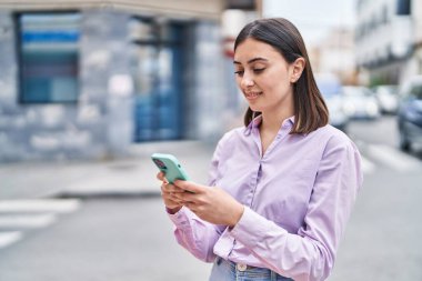 Sokakta akıllı telefon kullanan, kendine güvenen genç İspanyol kadın.