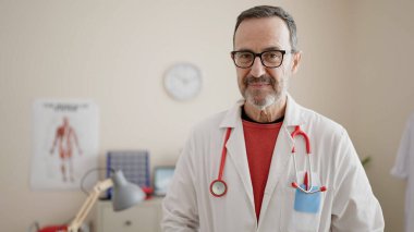 Çağrı merkezi kulaklığı takan orta yaşlı bir adam mutlu bir gülümseme ve el kaldırarak zaferi kutluyor. 