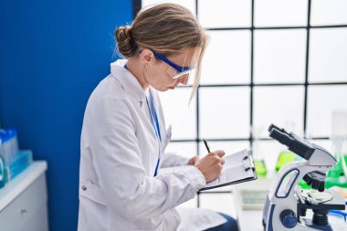 Genç sarışın bilim kadını laboratuarda çalışıyor.