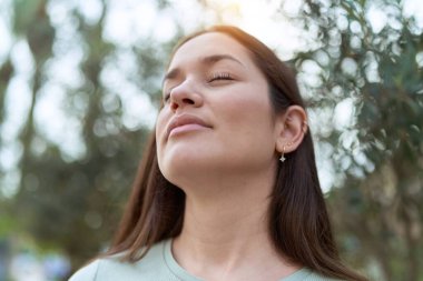 Parkta gözleri kapalı nefes alan genç ve güzel bir kadın.