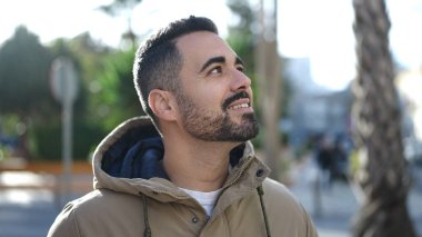 Young hispanic man smiling confident looking to the sky at park