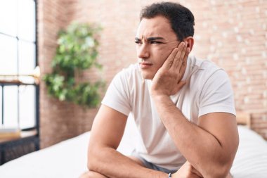 Genç İspanyol adam yatakta otururken stresli.