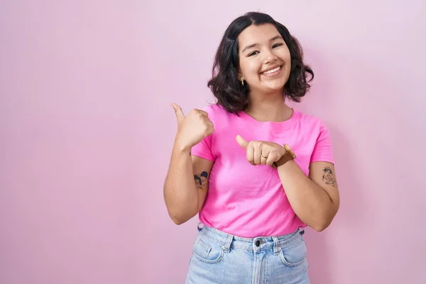 Young Hispanic Woman Standing Pink Background Pointing Back Hand Thumbs — Fotografia de Stock