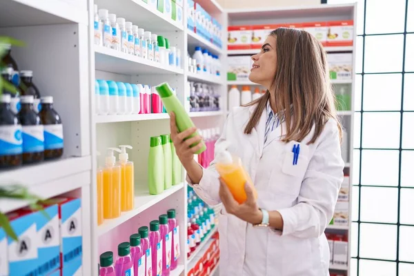 Young Beautiful Hispanic Woman Pharmacist Holding Shampoo Bottles Pharmacy — Stockfoto