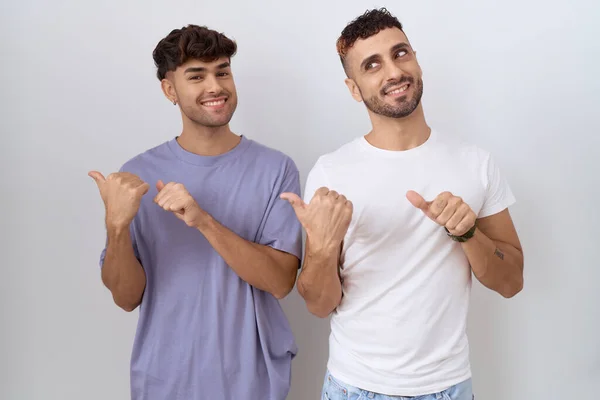 同性恋夫妇站在白色的背景上 手背朝后 竖起大拇指 带着自信的微笑 — 图库照片