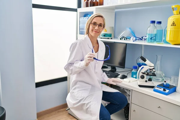 Νεαρή Ξανθιά Γυναίκα Επιστήμονας Χαμογελά Αυτοπεποίθηση Κρατώντας Γυαλιά Στο Εργαστήριο — Φωτογραφία Αρχείου