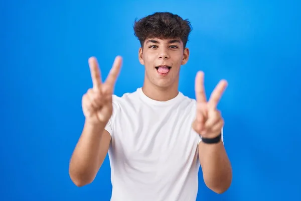 Adolescente Hispânico Sobre Fundo Azul Sorrindo Com Língua Para Fora — Fotografia de Stock