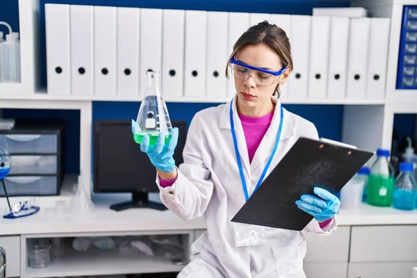 Young Beautiful Hispanic Woman Scientist Reading Report Holding Test Tube — Stock Fotó
