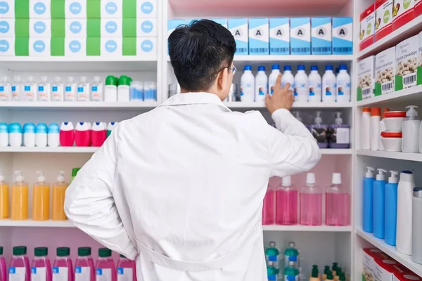 Молодой Китайский Фармацевт Держит Товар Полках Аптеке — стоковое фото