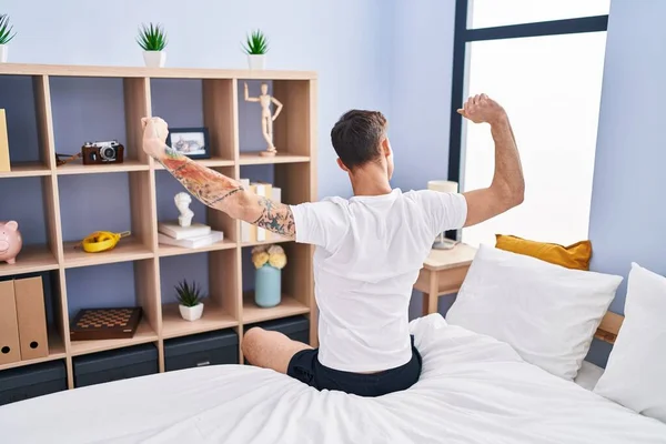 Stock image Young man waking up stretching arms on back view at bedroom