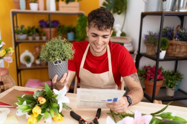 Çiçekçi dükkanında elinde bitki tutan İspanyol bir çiçekçi.