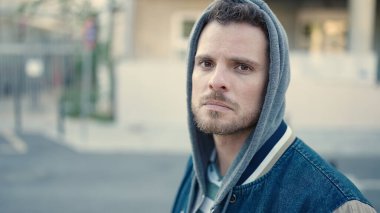 Young caucasian man standing wearing hoodie with serious expression at street