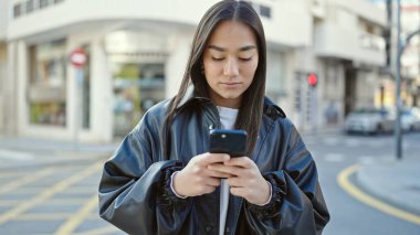 Genç ve güzel İspanyol kadın akıllı telefon kullanıyor. Sokakta ciddi bir ifadesi var.