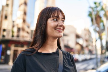 Young beautiful hispanic woman smiling confident looking to the side at street