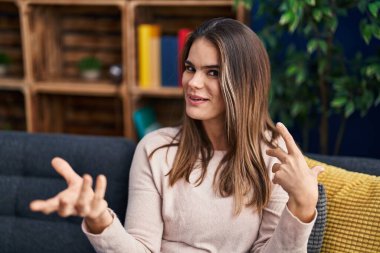 Kanepede oturan genç, güzel İspanyol kadın evde konuşuyor.