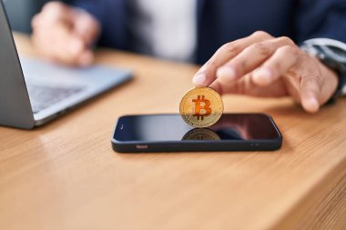 Genç İspanyol iş adamı ofisteki akıllı telefona bitcoin yerleştiriyor.
