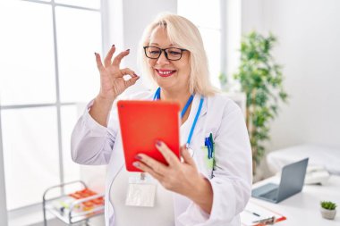 Orta yaşlı, beyaz bir kadın online randevuda çalışıyor. Parmaklarıyla imza atıyor, gülümsüyor. Mükemmel bir sembol. 