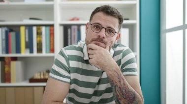 Kütüphane üniversitesinde düşünen beyaz bir genç.