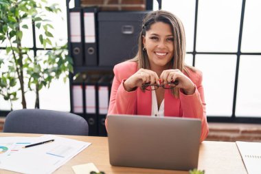 Ofiste çalışan genç İspanyol iş kadını laptopu kullanıyor.