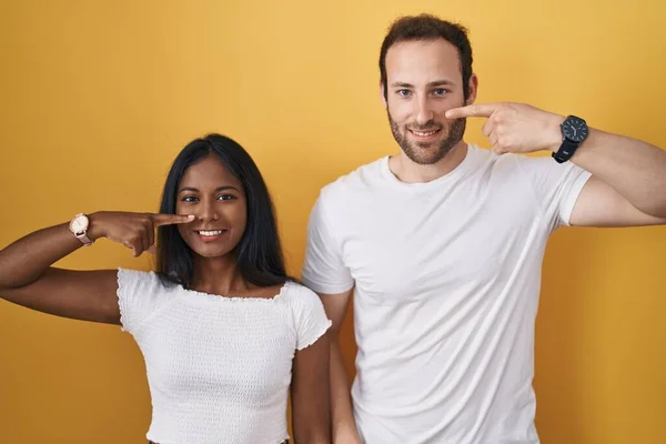 Interracial Couple Standing Yellow Background Pointing Hand Finger Face Nose — Stock Photo, Image