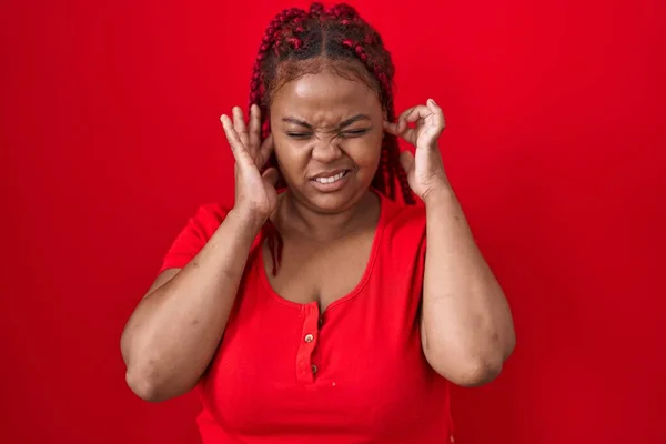 Африканская Американка Плетеными Волосами Стоит Красном Фоне Закрывая Уши Пальцами — стоковое фото