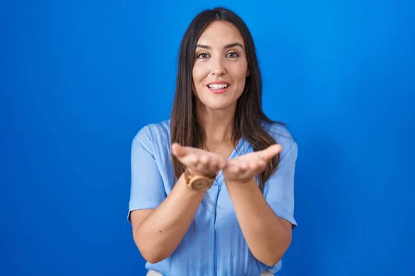 Jonge Brunette Vrouw Staat Blauwe Achtergrond Glimlachend Met Handen Palmen — Stockfoto