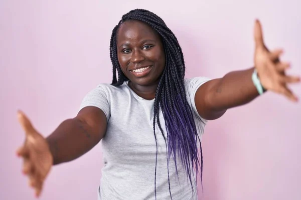 Fiatal Afrikai Áll Rózsaszín Háttér Nézi Kamera Mosolygó Tárt Karokkal — Stock Fotó