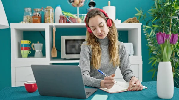 食堂でノートパソコンを使ってノートを書く若い白人女性学生 — ストック写真