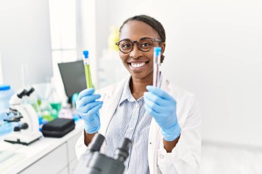 Laboratuvarda test tüpleri tutan Afrikalı Amerikalı kadın bilim adamı.