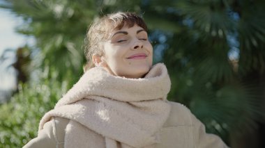 Young caucasian woman smiling confident with closed eyes enjoying sunlight at park