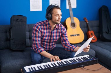 Young man musician playing piano keyboard at music studio