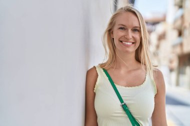 Young blonde woman smiling confident looking to the side at street
