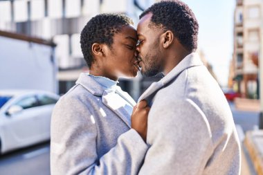 Man and woman couple hugging each other and kissing at street